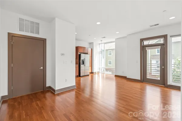 a view of an empty room with window and wooden floor