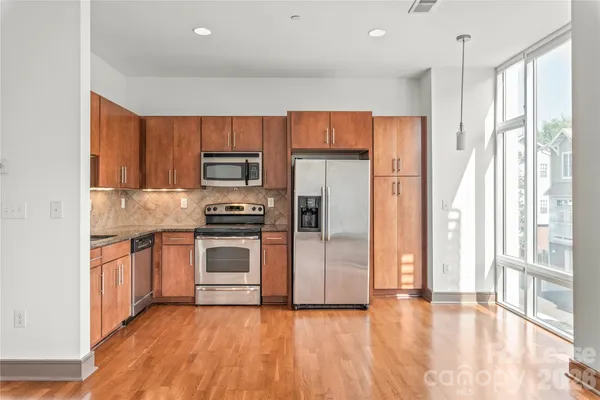 a kitchen with granite countertop a refrigerator and a stove top oven