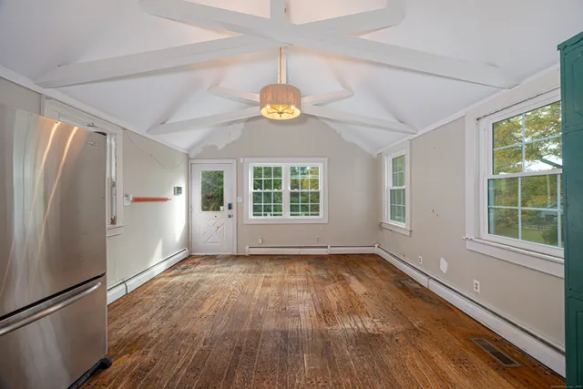 a view of an empty room with a window and wooden floor
