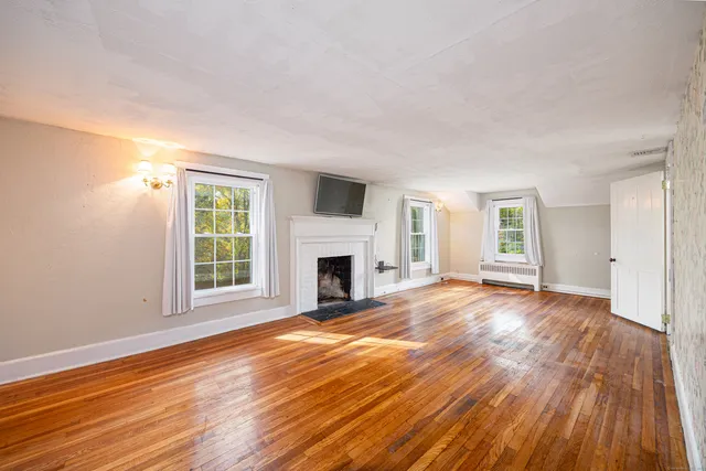 a view of empty room with wooden floor and fireplace