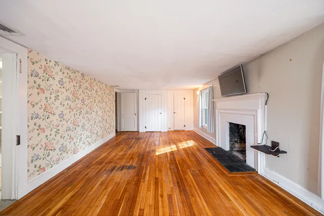 a view of a livingroom with wooden floor and a fireplace