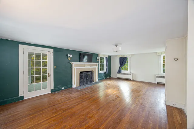 an empty room with wooden floor fireplace and windows