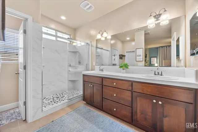 a bathroom with a double vanity sink mirror and shower