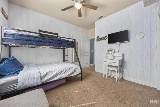 a bedroom with a bed tv and a chair