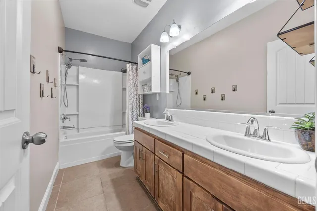 a bathroom with a double vanity sink toilet mirror and shower