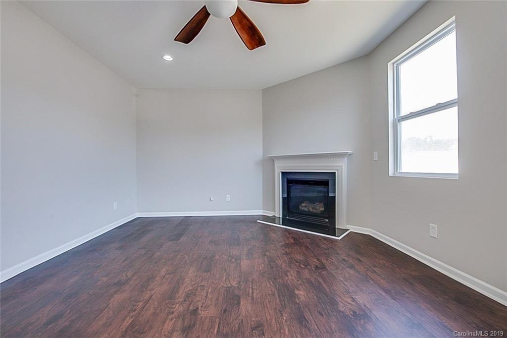1022 Yellow Bee Road Indian Trail, NC 28079 - Photo 4 of 20 an empty room with wooden floor fireplace and windows