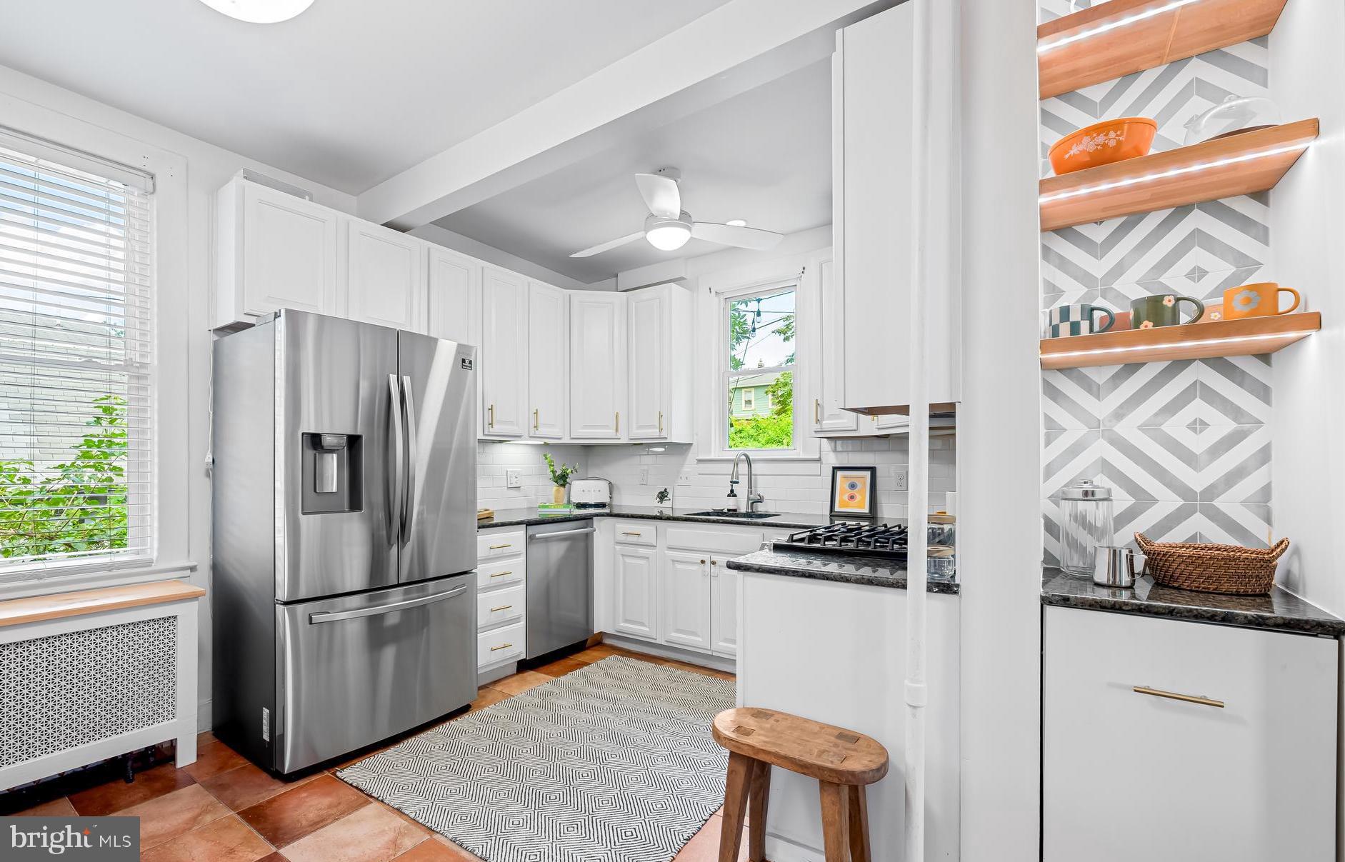 5009 Catalpha Road Baltimore, MD 21214 - Photo 12 of 38 a kitchen with stainless steel appliances a refrigerator a stove a sink and white cabinets with wooden floor
