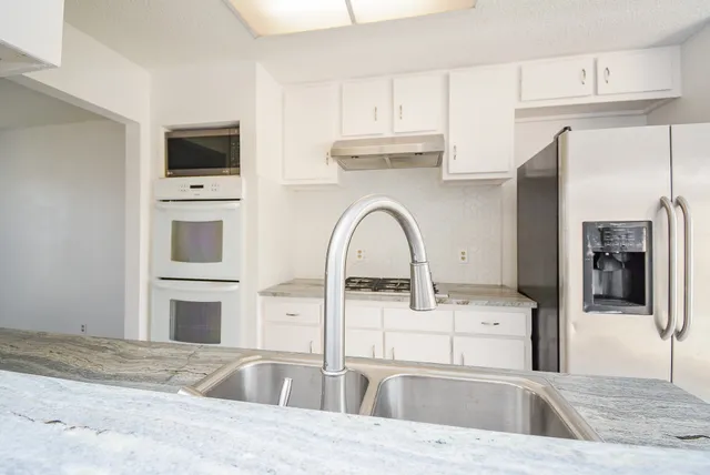 a kitchen with stainless steel appliances kitchen island a white counter tops and white cabinets
