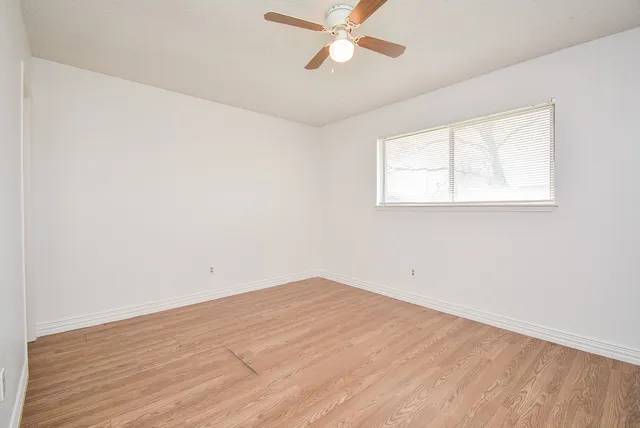 an empty room with a window and a ceiling fan