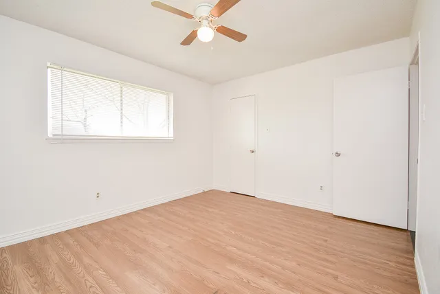 an empty room with a window and a ceiling fan