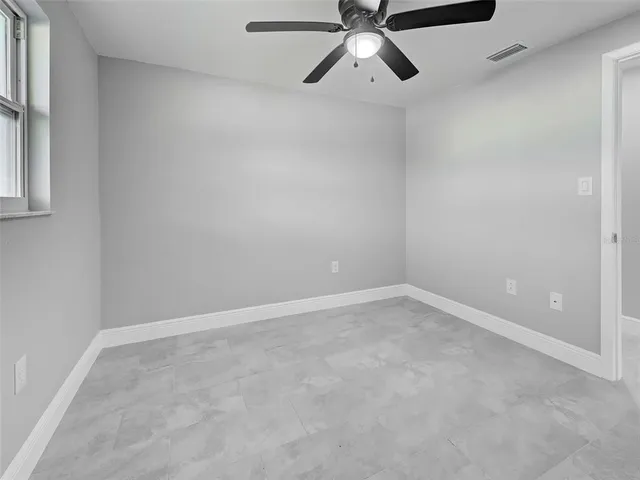 an empty room with a window and a ceiling fan