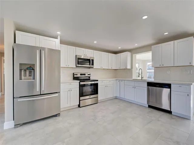 a kitchen with granite countertop a refrigerator and a stove top oven