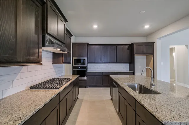 a kitchen with granite countertop a sink a stove and cabinets