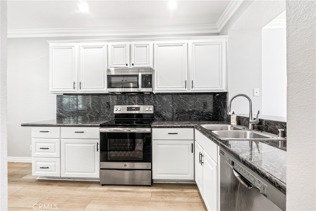 20301 Bluffside Circle, Unit 304 Huntington Beach, CA 92646 - Photo 20 of 36 a kitchen with stainless steel appliances granite countertop a stove a sink and white cabinets