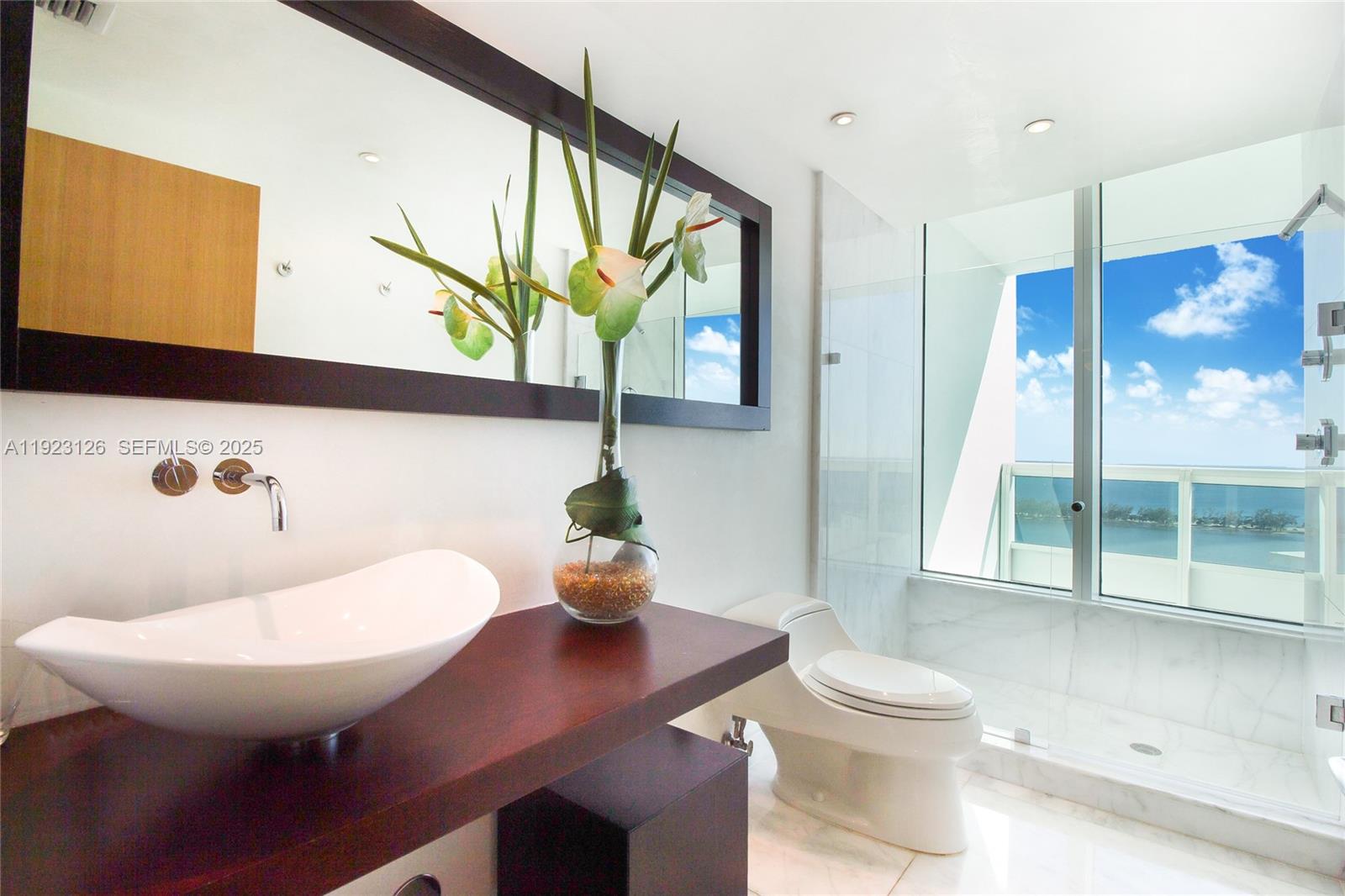 1643 Brickell Avenue, Unit 2902 Miami, FL 33129 - Photo 22 of 41 a bathroom with a toilet a sink and a large mirror