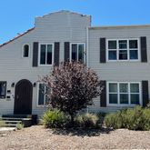 a front view of a house with plants and garden