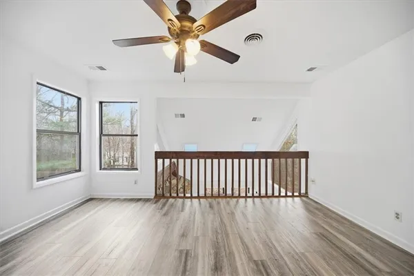 a view of an empty room with wooden floor and a window