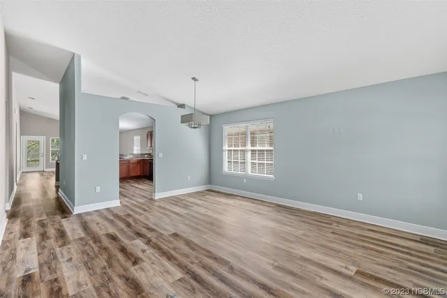 a living room with furniture a flat screen tv and a refrigerator