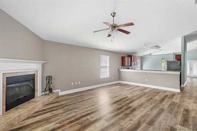 a view of an empty room with a window and a kitchen
