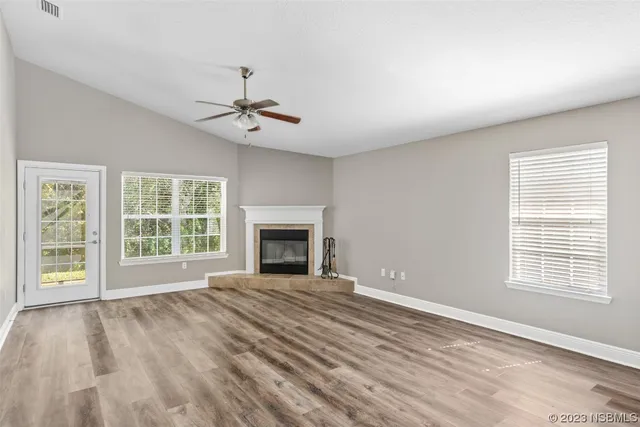 wooden floor fireplace and windows in an empty room