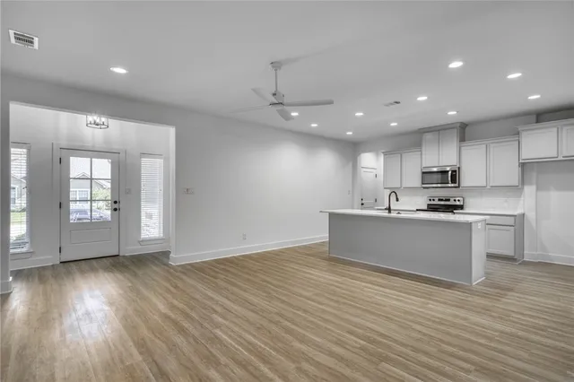 a view of kitchen with granite countertop cabinets wooden floor and stainless steel appliances