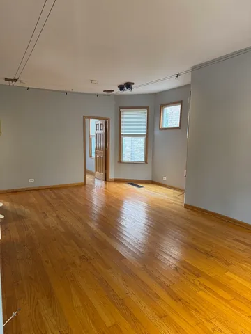 a view of an empty room with window and wooden floor