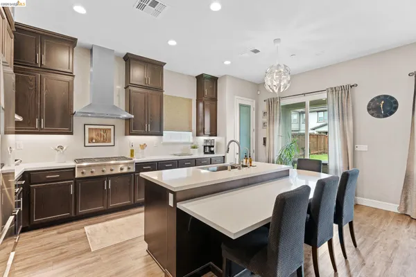a kitchen with stainless steel appliances granite countertop a sink a stove a refrigerator a dining table and chairs