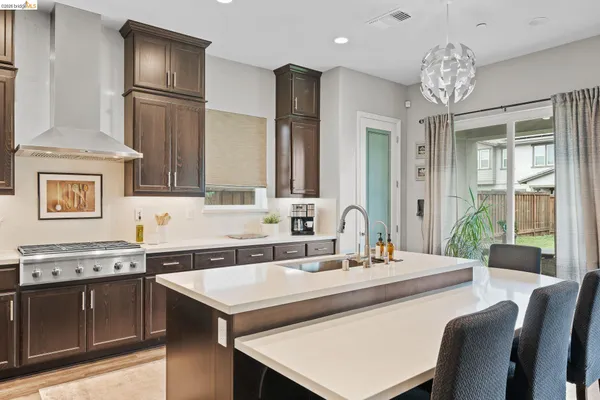 a kitchen with a stove a sink dishwasher a refrigerator and a dining table with wooden floor