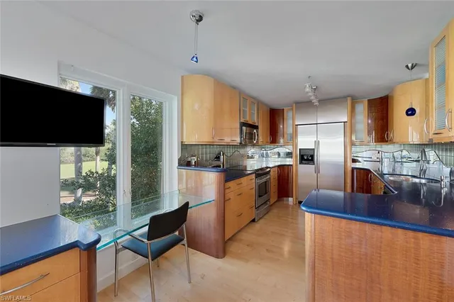 a kitchen with stainless steel appliances granite countertop a sink a stove a refrigerator cabinets and living room view