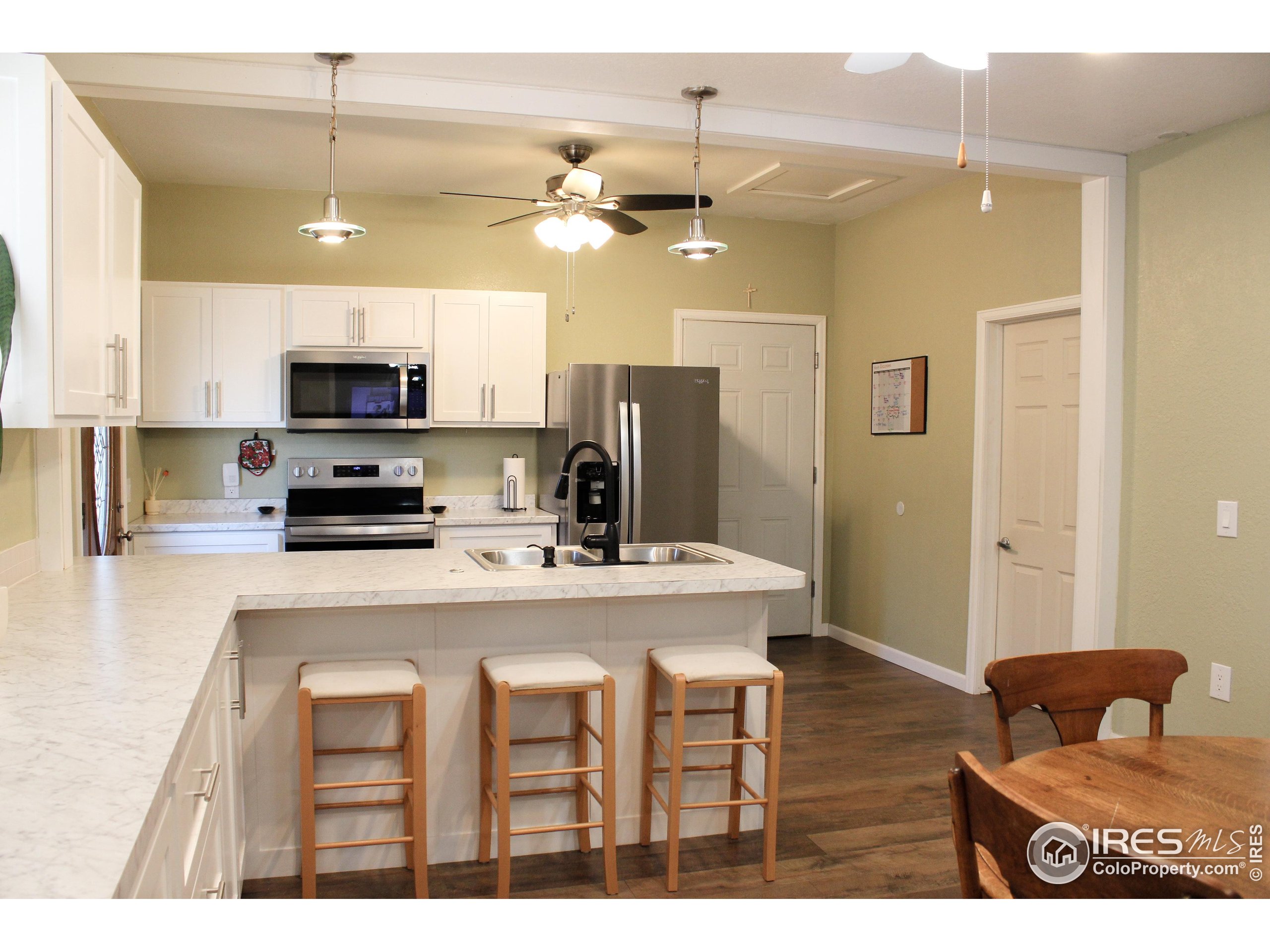 504 12th Street Greeley, CO 80631 - Photo 7 of 19 a kitchen with kitchen island granite countertop a stove a sink a refrigerator and a microwave