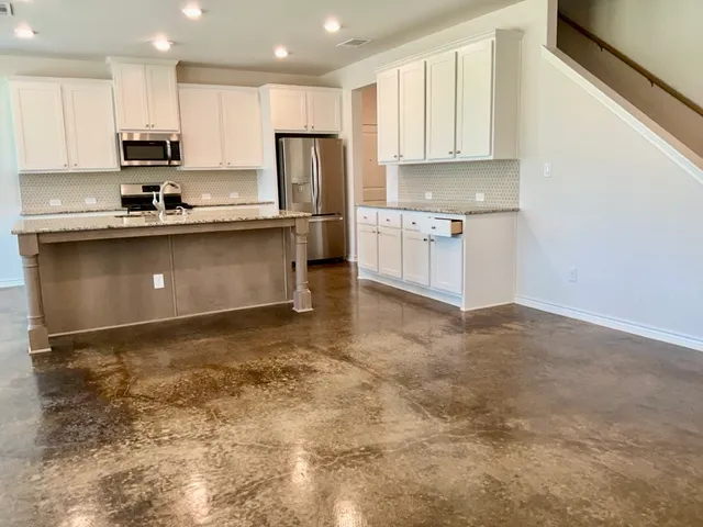 a kitchen with stainless steel appliances granite countertop a refrigerator a stove a sink and white cabinets