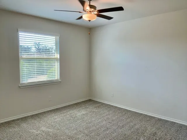 an empty room with a window and a fan