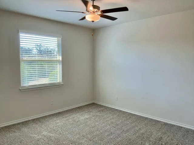 an empty room with a window and a fan