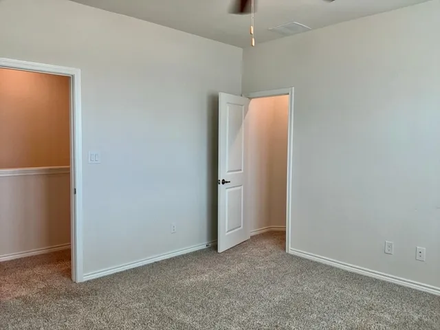 an empty room with closet and a chandelier fan