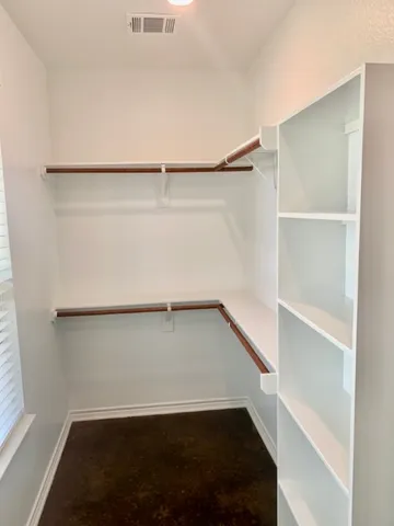 a view of walk in closet with empty racks