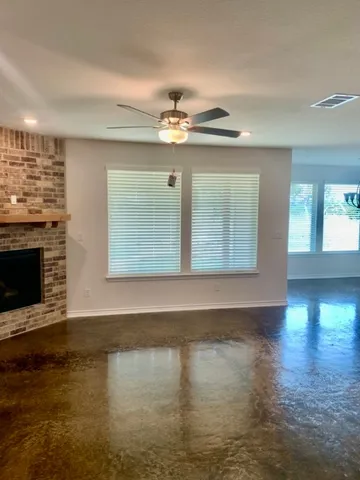 a view of an empty room with wooden floor and a fireplace