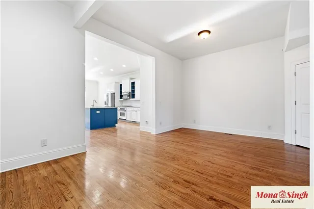 a view of empty room with wooden floor and kitchen view