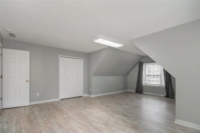 a view of an empty room with window and wooden floor
