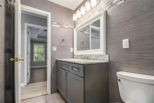 a bathroom with a granite countertop toilet a sink and a mirror