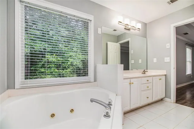 a bathroom with a bathtub a sink a vanity and a large mirror