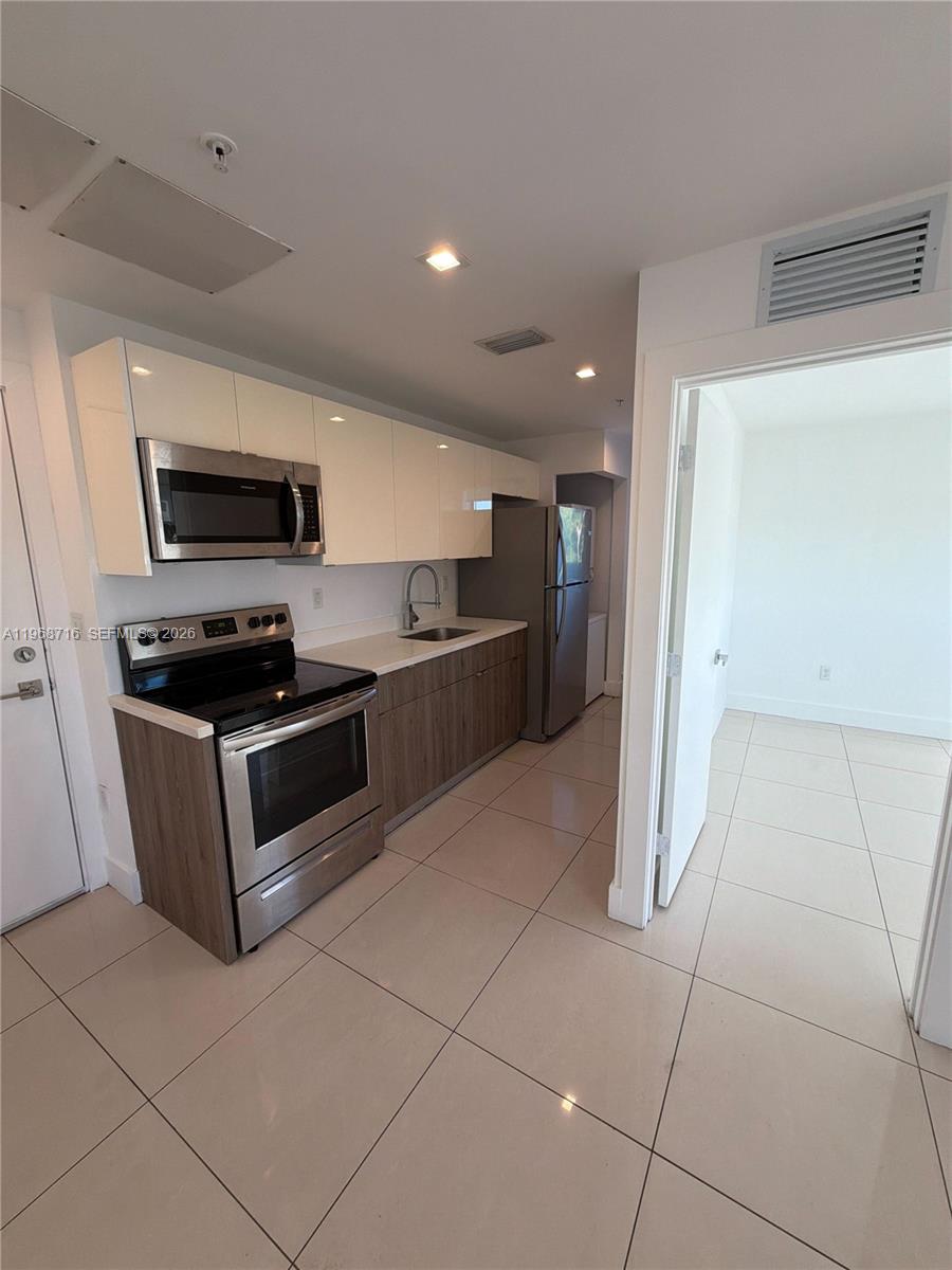 829 Southwest 18th Avenue, Unit 311 Miami, FL 33135 - Photo 3 of 11 a kitchen with stainless steel appliances granite countertop a refrigerator and a stove top oven