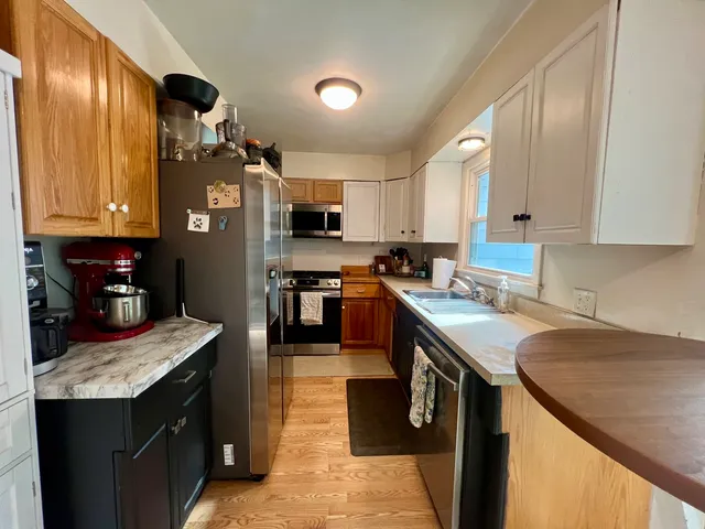 a kitchen with kitchen island granite countertop a sink a stove top oven a counter space and cabinets