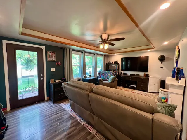 a living room with furniture a ceiling fan and a flat screen tv