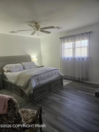 a bedroom with a bed and a dresser with wooden floor