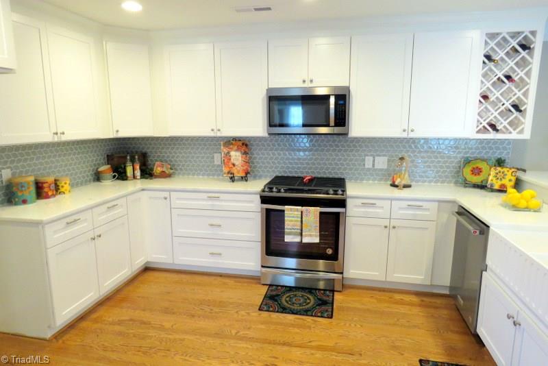 8529 Lasater Road Clemmons, NC 27012 - Photo 7 of 30 All NEW Kitchen: Beautiful granite counters, bright white cabinets, tile backsplash, under cabinet lighting, built-in wine rack, farm sink and Stainless Steel appliances.