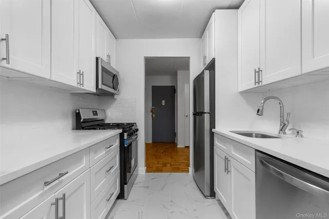 a kitchen with stainless steel appliances granite countertop white cabinets and a stove