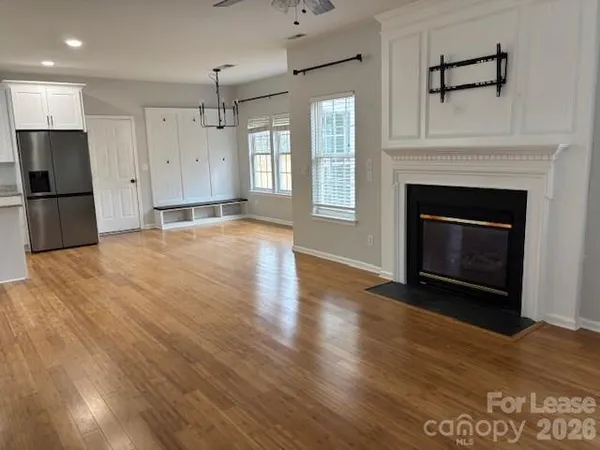 a view of an empty room with wooden floor fireplace and a window