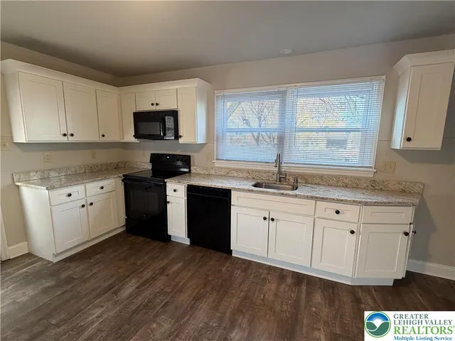 a kitchen with granite countertop white cabinets sink and stainless steel appliances