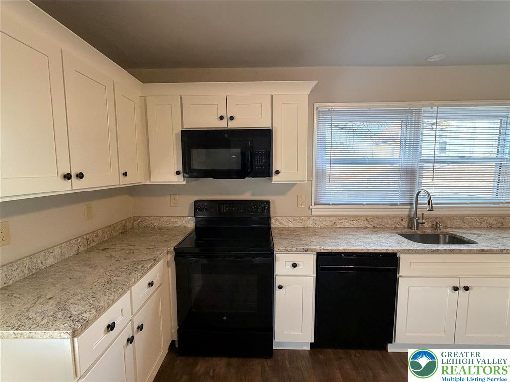 32 North Front Street Coplay, PA 18037 - Photo 8 of 14 a kitchen with granite countertop a sink dishwasher a stove and a microwave oven with cabinets