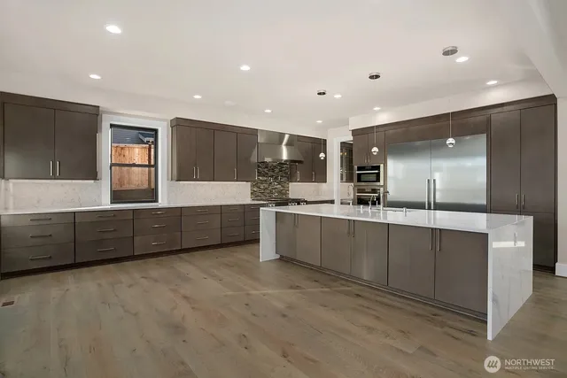 a large kitchen with a large counter top a sink stainless steel appliances and cabinets